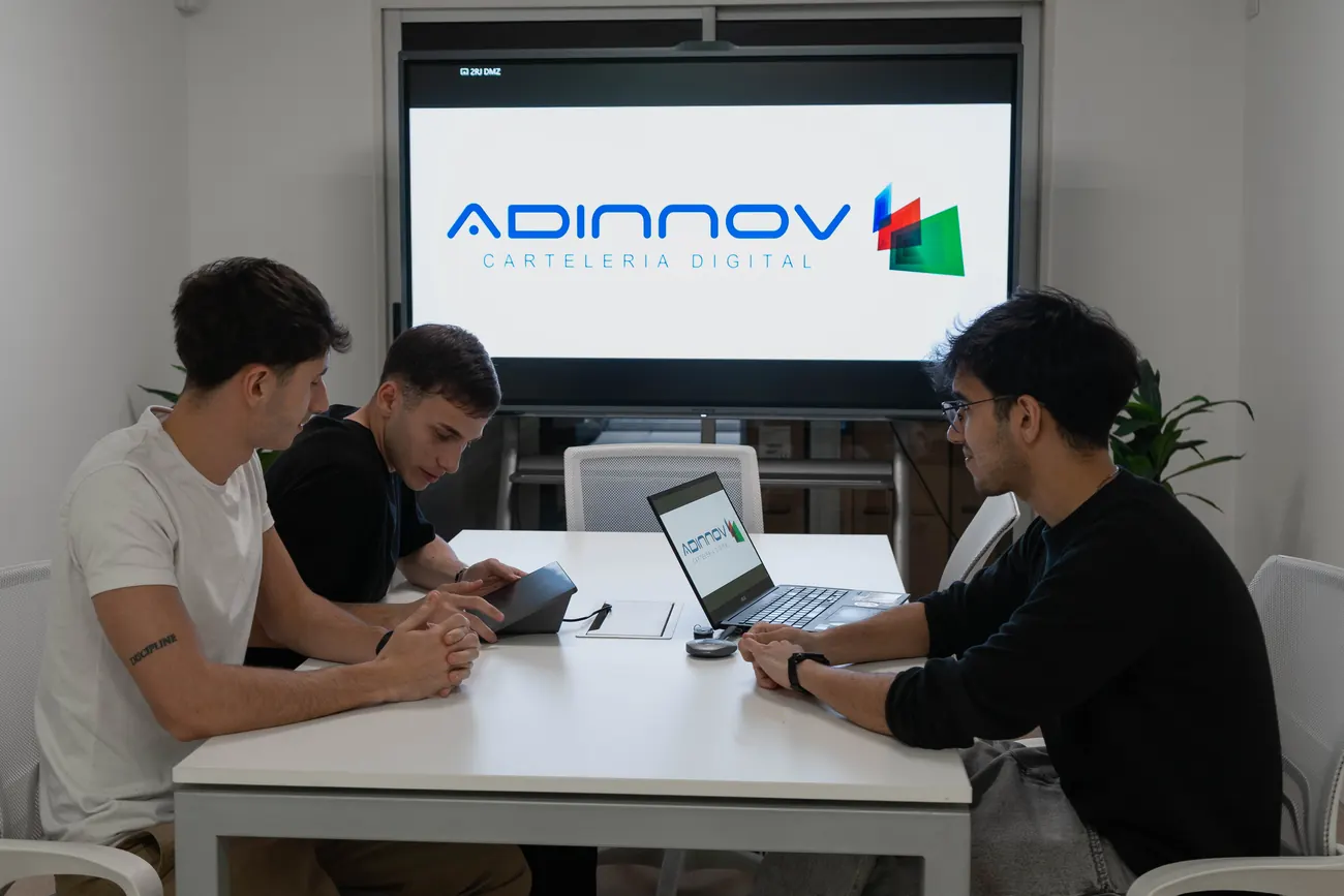 Tres integrantes del equipo trabajando juntos alrededor de una mesa
